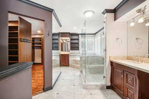 Master bathroom featuring huge closet organizer system, walk in shower, double sinks, vanity, a full wall mirror and crown molding