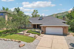 View of front of house with a garage, a mountain view, and a front lawn