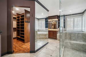 Bathroom featuring full wall mirror, walk in shower, huge closet organizer system, tile patterned floors, vanity, and separate shower and jettedtub