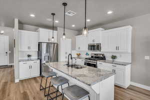 Kitchen featuring white cabinetry, stainless steel appliances, and sink