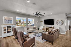 Living room featuring ceiling fan, a textured ceiling, and light hardwood / wood-style floors