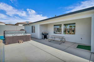 View of patio with a hot tub and area for grilling