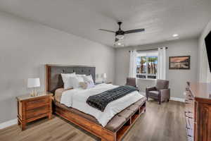 Bedroom with ceiling fan, a textured ceiling, and light wood-type flooring