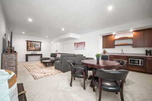 Dining room featuring light carpet, wine cooler, a textured ceiling, and wet bar