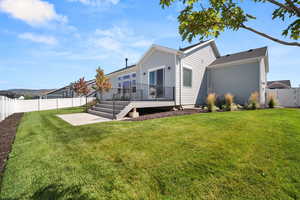 Rear view of property with a wooden deck, a patio, and a lawn