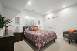 Bedroom with light colored carpet and a closet