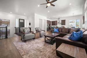 Living room with ceiling fan, a textured ceiling, and light wood-type flooring