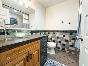 Bathroom featuring vanity, tile walls, tile patterned floors, and toilet