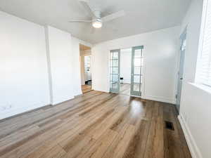 Spare room with a wealth of natural light, light hardwood / wood-style floors, french doors, and ceiling fan