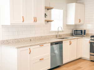 Kitchen featuring tasteful backsplash, sink, white cabinets, and appliances with stainless steel finishes