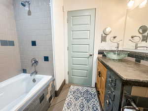 Bathroom featuring vanity, tile patterned floors, and tiled shower / bath