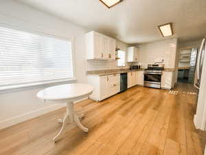 Kitchen with white cabinetry, tasteful backsplash, appliances with stainless steel finishes, and light hardwood / wood-style flooring