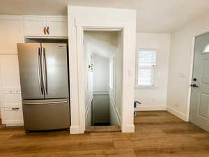 Interior space featuring white cabinetry, stainless steel fridge, a textured ceiling, and light hardwood / wood-style flooring