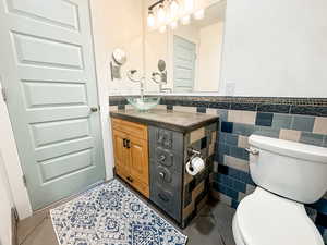 Bathroom with tile patterned flooring, vanity, tile walls, and toilet