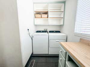 Washroom with cabinets, washing machine and dryer, and dark tile patterned flooring