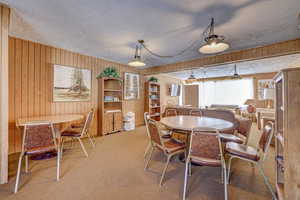 Dining space featuring carpet, a textured ceiling, and wood walls