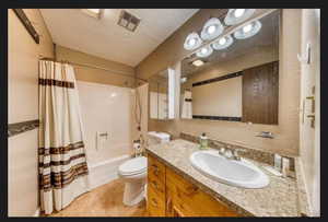 Full bathroom with shower / tub combo with curtain, vanity, tile patterned flooring, and toilet