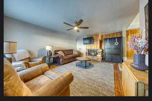 Living room with hardwood / wood-style flooring, ceiling fan, a textured ceiling, and wood walls