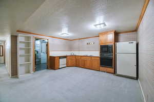 Kitchen featuring crown molding, light colored carpet, washer / dryer, and black appliances