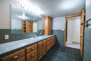 Bathroom with vanity, tile patterned floors, and a textured ceiling