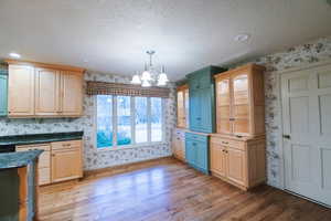 Kitchen featuring an inviting chandelier, decorative light fixtures, light hardwood / wood-style flooring, and a textured ceiling