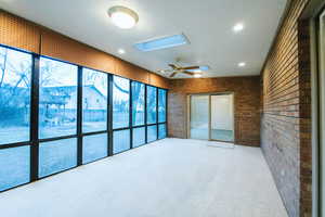 Unfurnished sunroom featuring ceiling fan