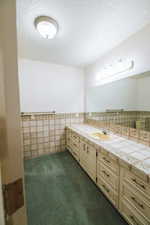 Bathroom featuring vanity, tile walls, and a textured ceiling