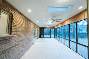 Unfurnished sunroom with a skylight and ceiling fan