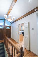 Entrance foyer featuring a notable chandelier, lofted ceiling with beams, a textured ceiling, and light wood-type flooring