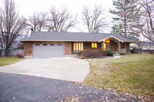 Ranch-style house featuring a garage and a front lawn