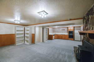 Basement featuring light carpet, wooden walls, a textured ceiling, and white refrigerator