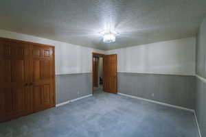 Carpeted spare room featuring a textured ceiling