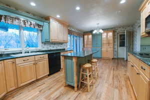 Kitchen with a kitchen island, pendant lighting, sink, a kitchen bar, and black appliances