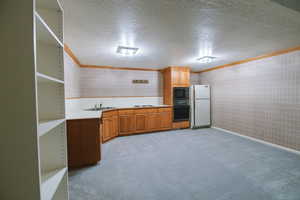 Kitchen featuring sink, crown molding, a textured ceiling, light colored carpet, and black appliances