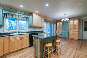 Kitchen featuring dishwasher, sink, a kitchen island, and light hardwood / wood-style flooring