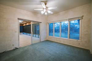 Carpeted empty room featuring a textured ceiling and ceiling fan