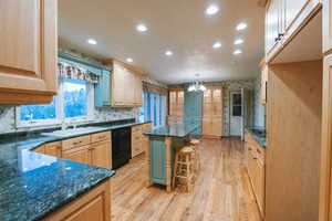 Kitchen featuring sink, hanging light fixtures, a kitchen breakfast bar, a center island, and black appliances