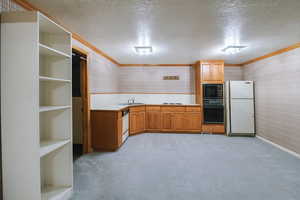 Kitchen featuring ornamental molding, sink, light carpet, and black appliances