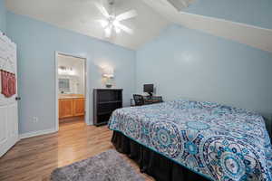 Bedroom featuring lofted ceiling, ensuite bathroom, ceiling fan, and light wood-type flooring