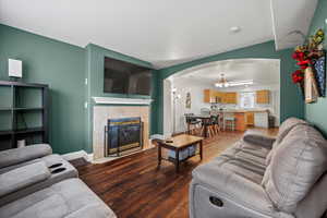 Living room featuring hardwood / wood-style flooring, a tiled fireplace, and an inviting chandelier