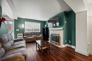 Living room with dark wood-type flooring, a textured ceiling, and a fireplace