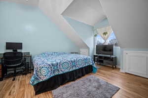 Bedroom with lofted ceiling and light wood-type flooring