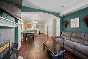 Living room featuring a tiled fireplace, dark wood-type flooring, and a notable chandelier