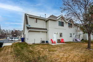 Back of property with cooling unit, a yard, and a patio area