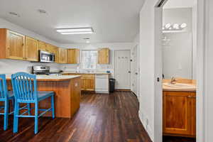 Kitchen featuring appliances with stainless steel finishes, dark hardwood / wood-style floors, sink, and a kitchen breakfast bar