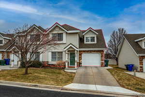 View of front facade featuring a garage and a front lawn