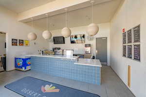 Interior space featuring a high ceiling, light tile patterned flooring, and hanging light fixtures