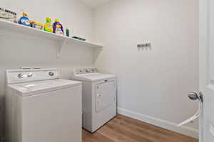 Clothes washing area featuring washer and clothes dryer and light hardwood / wood-style flooring