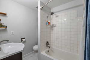 Full bathroom with vanity, shower / bathtub combination with curtain, and toilet