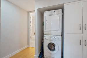 Clothes washing area featuring stacked washer / drying machine and light hardwood / wood-style flooring